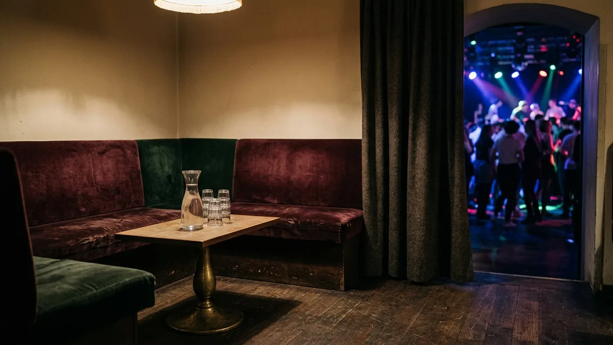 Ruhiger Rückzugsraum mit Sofa und gedämpftem Licht abseits des Dancefloors