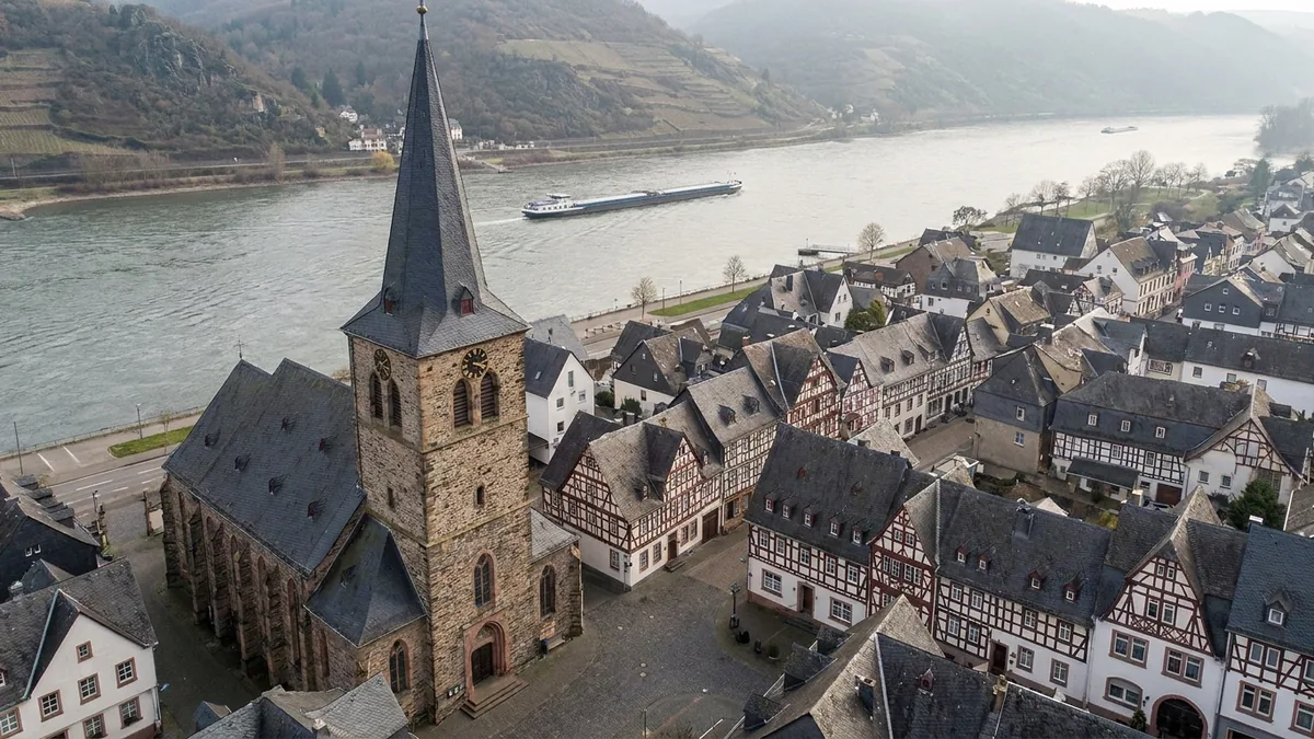 Blick über eine rheinische Kleinstadt am Fluss mit Kirchturm und Uferpromenade