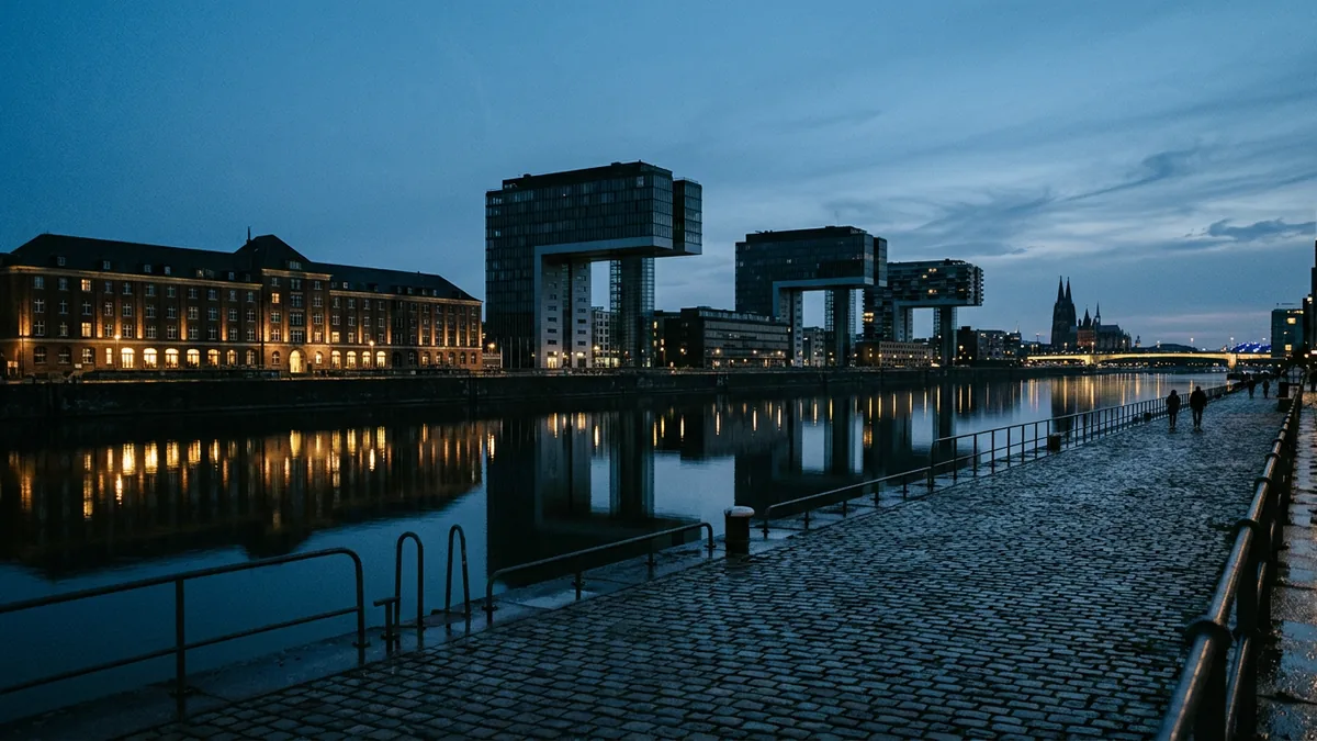 Rheinauhafen in Köln bei Dämmerung, Kranhäuser im Gegenlicht, beleuchtete Fenster der Hafenzeile