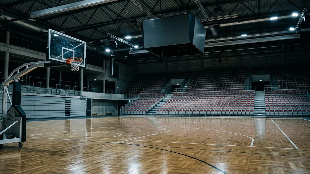 Korbanlage und dunkle Anzeigetafel in einer leeren Basketballhalle vor dem Spiel
