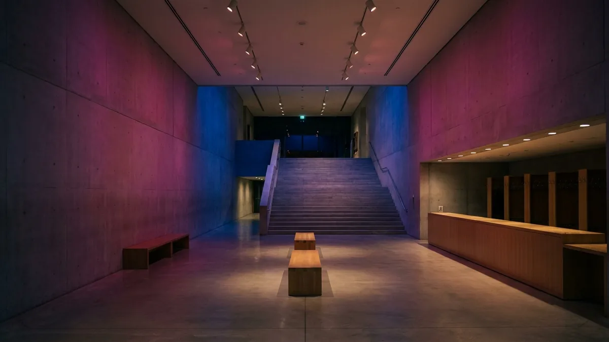 Museumsfoyer bei Nacht mit breiter Steintreppe und farbigem Bühnenlicht