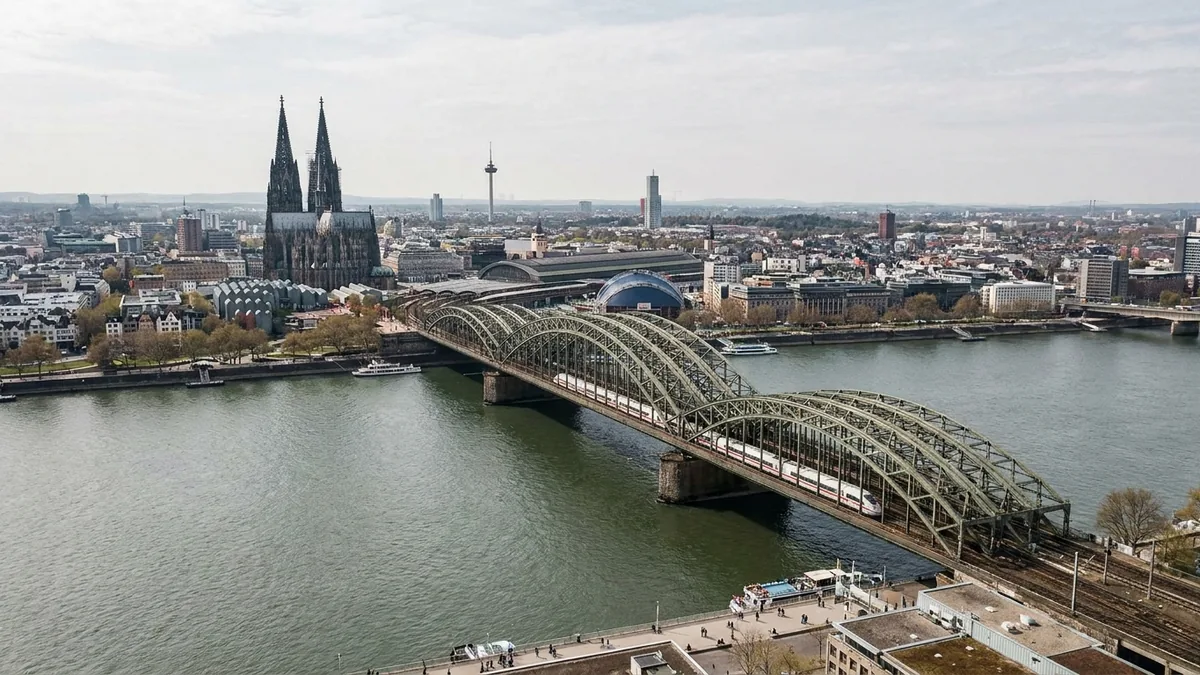 Luftaufnahme der Hohenzollernbrücke über den Rhein mit einem ICE, dahinter Dom und Hauptbahnhof